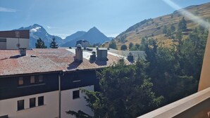 Un edificio con techo de tejas rojas, varias chimeneas y vista a las montañas al fondo.