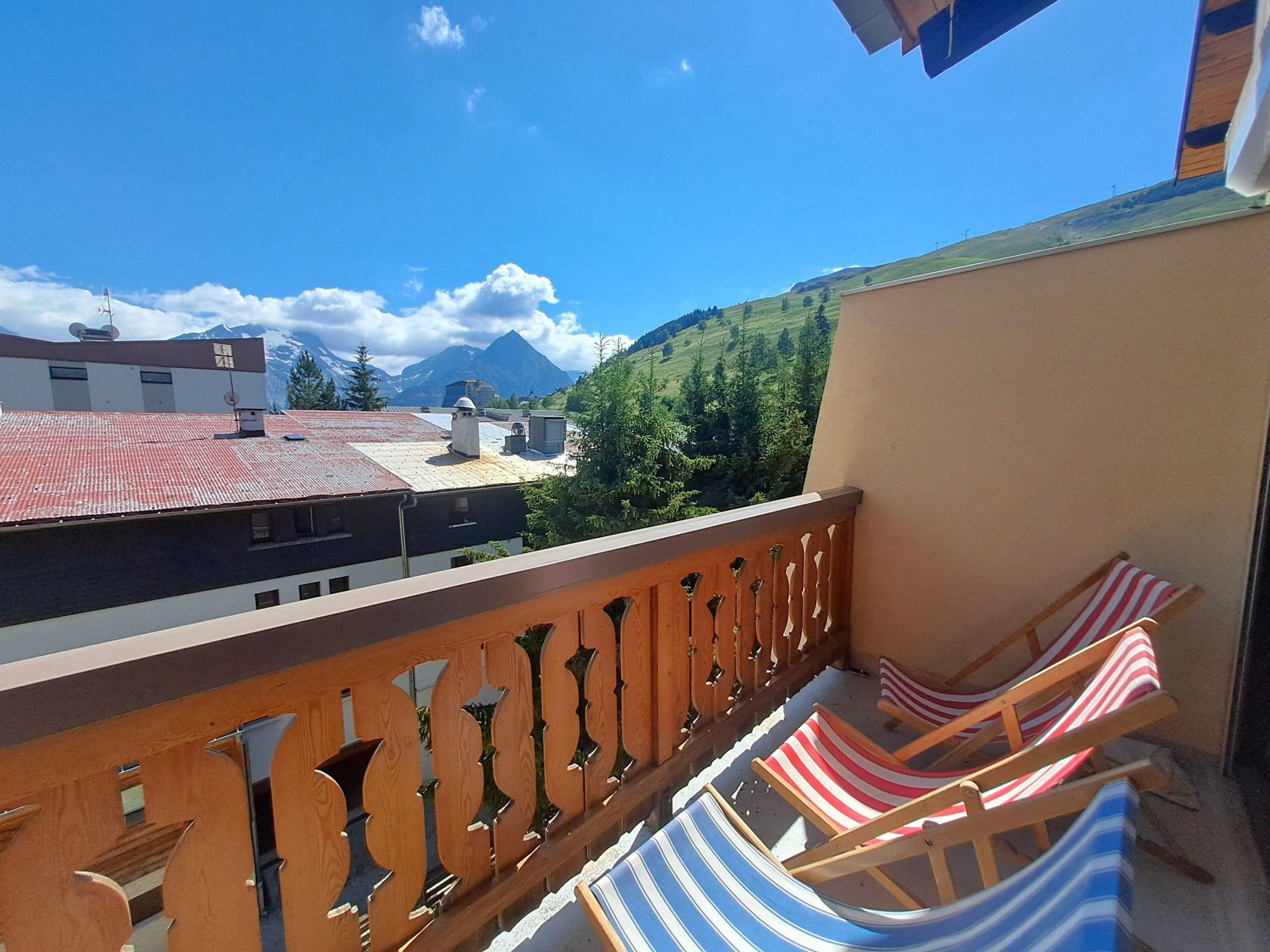 Ein Balkon mit Blick auf Berge und ein Gebäude mit rotem Dach.