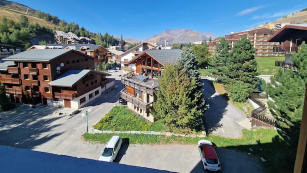 Un complejo turístico de montaña con edificios de madera, un estacionamiento y vistas a montañas al fondo.
