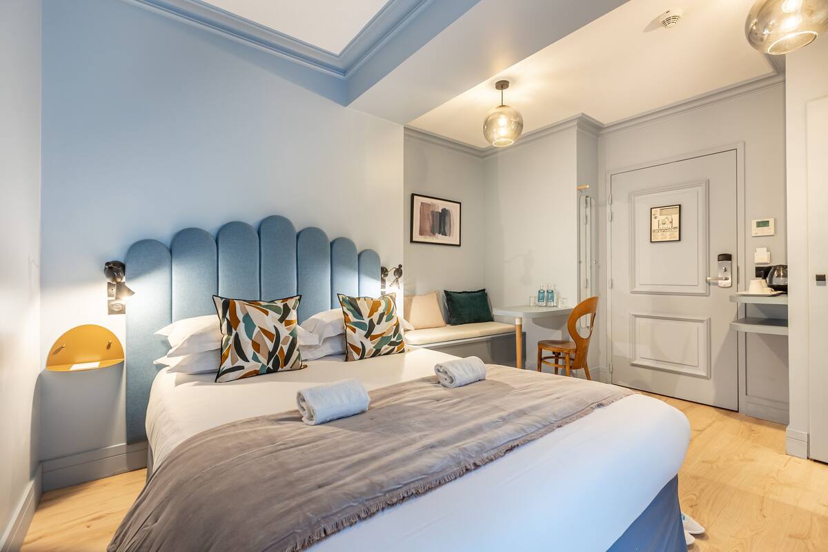A neatly arranged bedroom with a large bed, bedside tables, a desk, and a chair.