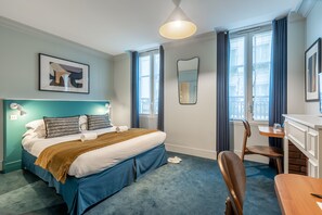 A modern hotel room with a large bed, a desk, and a chair.