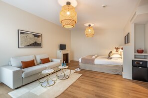A modern hotel room with a sofa, a bed, a small table, and a wall-mounted TV.