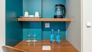A wooden table with a coffee maker, two bottles of water, and three glasses. - Le Nest by Sweett (Paris)