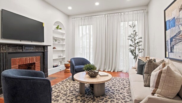 Ein modernes Wohnzimmer mit Kamin, Flachbildfernseher, rundem Couchtisch und einer Couch.