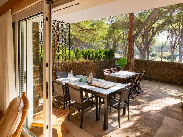 Un patio con una mesa y sillas, un banco de madera y una verja metálica decorativa.