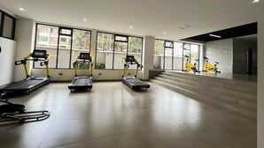 A spacious gym with treadmills, stationary bikes, and a mirror wall. - Lux Suites Perry West Luxurios Apartment (Nairobi)
