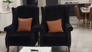 A modern living room with two black armchairs with orange cushions, a white coffee table, and a grey sofa. - Lux Suites Perry West Luxurios Apartment (Nairobi)