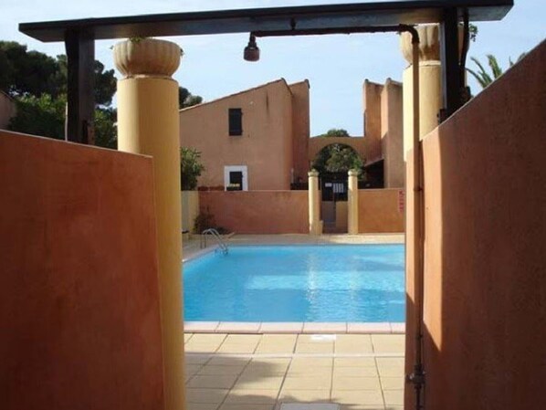 A swimming pool with a tiled deck, surrounded by walls with a simple architectural design.
