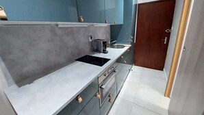 A modern kitchen with grey cabinets, a black stove, and a sink. - Modern Duplex Near Slopes, Ski Access (Les Deux Alpes)