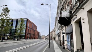 Calle con edificios, una vía de tranvía y aceras.