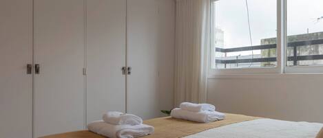 Une chambre d’hôtel avec un lit, une fenêtre avec des rideaux et une armoire.