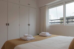 Une chambre d’hôtel avec un lit, une fenêtre avec des rideaux et une armoire.