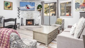 Un salon moderne avec une cheminée, une grande fenêtre et un coin salon confortable.