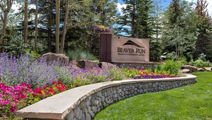 Une enseigne indiquant l’emplacement du complexe hôtelier et centre de conférences Beaver Run, entouré d’un jardin aménagé avec différentes variétés de fleurs et d’un mur de soutènement en pierre.