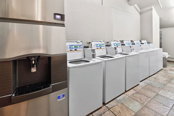 A row of self-service water dispensers and sinks in a public restroom.