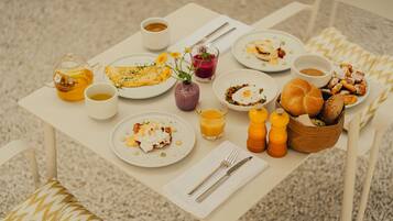 Una mesa de desayuno con varios platos, una tetera y una taza de café.