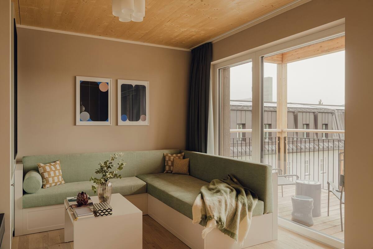 Un salon moderne avec un canapé vert, une table basse blanche et deux œuvres d’art abstraites encadrées accrochées au mur.