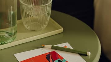 Ein grüner Tisch mit einer Glasflasche, einem Glas, einem Bleistift und einer roten Karte mit einer Tanzabbildung.