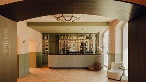 A hotel reception area with a wooden floor, a reception desk, and a seating area with two chairs. - Design Hotel zum Hirschen Salzburg (Salzburg)