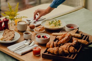 A breakfast tray with croissants, pastries, and a variety of fruits and beverages.
