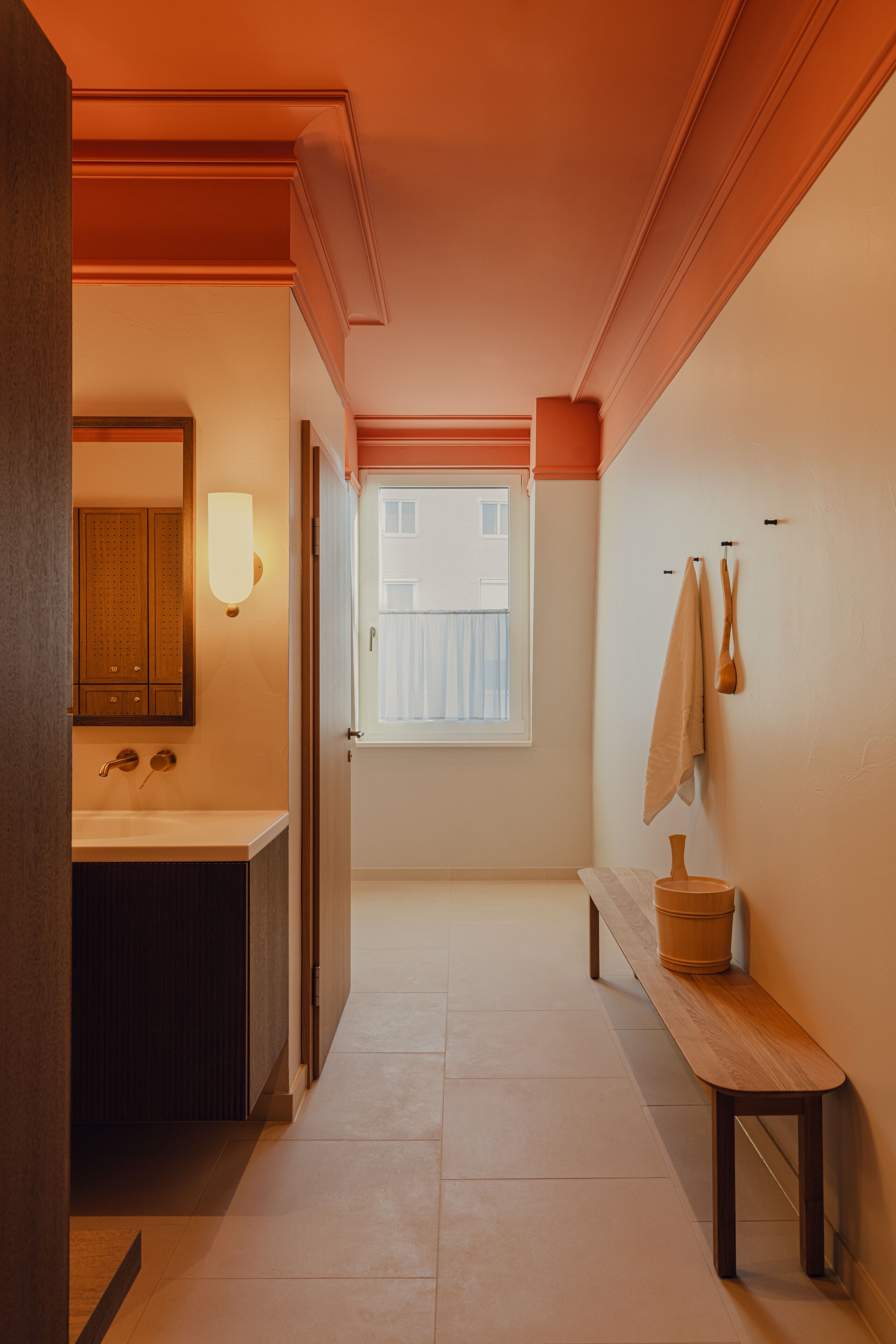 Un pasillo que conduce a un baño con lavamanos, espejo y toallero.