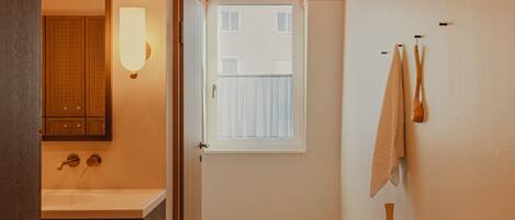 A hallway leading to a bathroom with a sink, mirror, and towel rack.