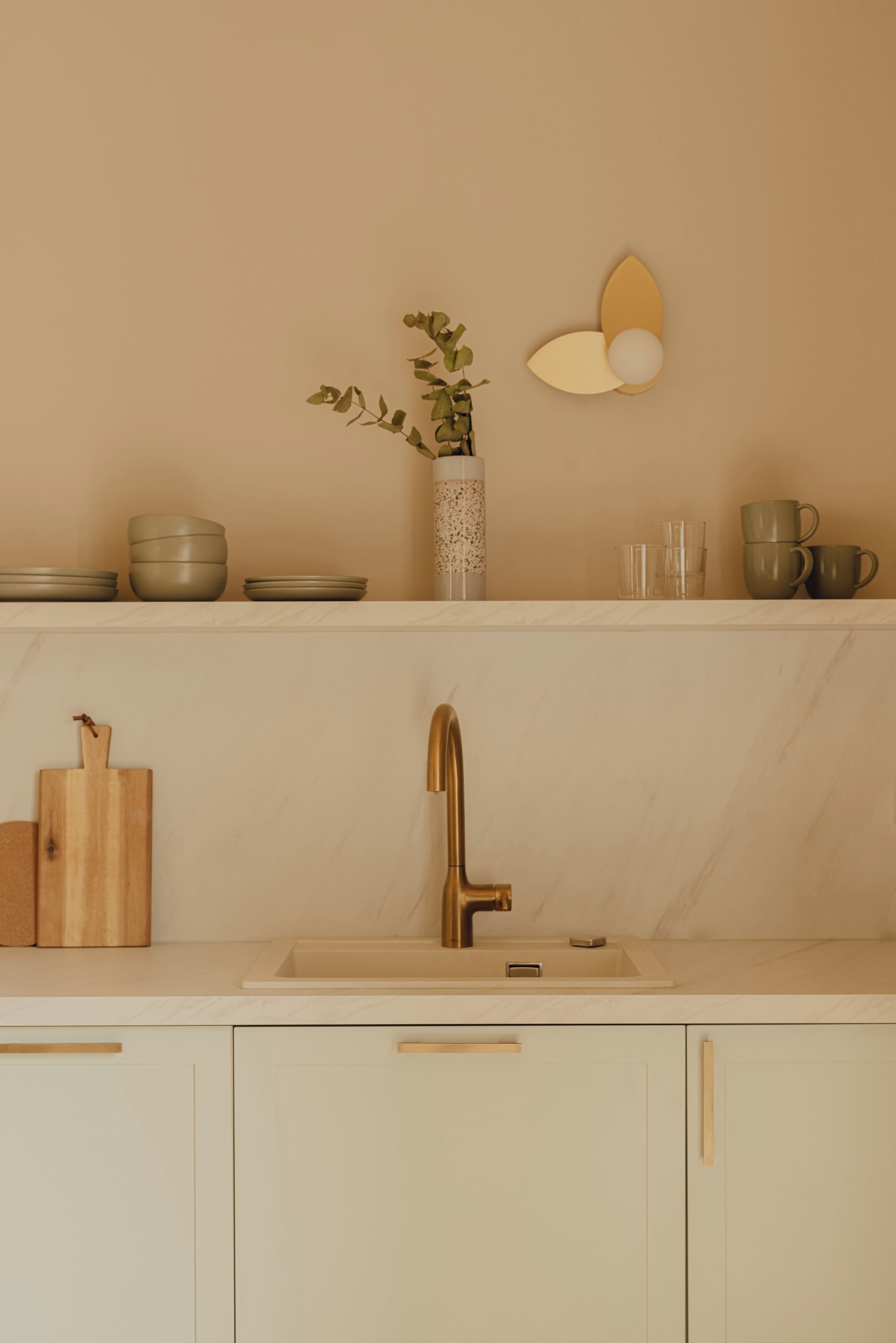A kitchen with a marble countertop, a gold faucet, and wooden cutting boards.