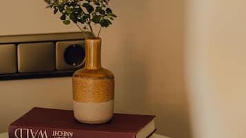 A white pedestal table with a vase containing a plant and a stack of books.