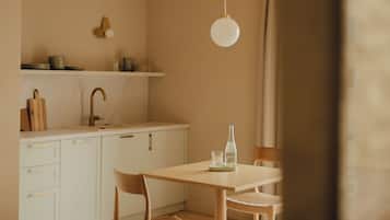 A kitchen with white cabinets, a wooden table, and a hanging light fixture.