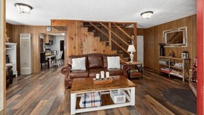 Ein gemütliches Wohnzimmer mit einem braunen Ledersofa, einem Holztisch und einer Treppe, die in einen anderen Raum führt.