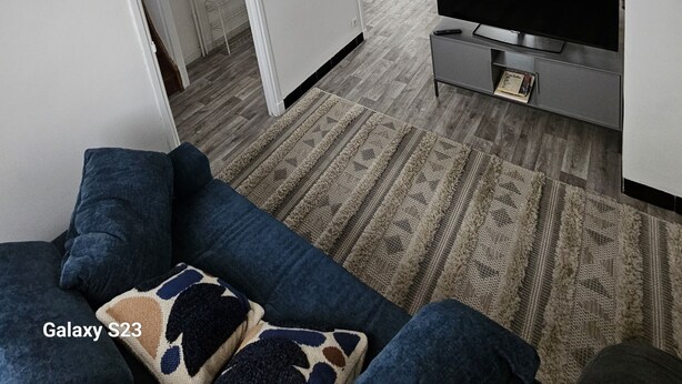 Een moderne woonkamer met een Galaxy S23 bank, een flatscreen televisie en een bijzondere lamp met touwen.