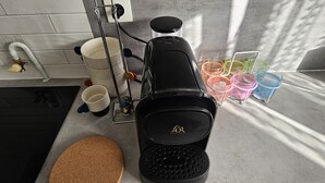 Een keuken met een koffiezetapparaat, een waterkoker en een koffiemolen op het aanrecht.