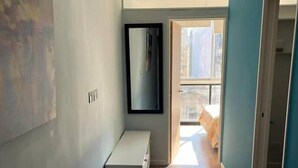 Ein schmaler Korridor mit einer Bank, einem Spiegel und einer Tür zum Balkon.