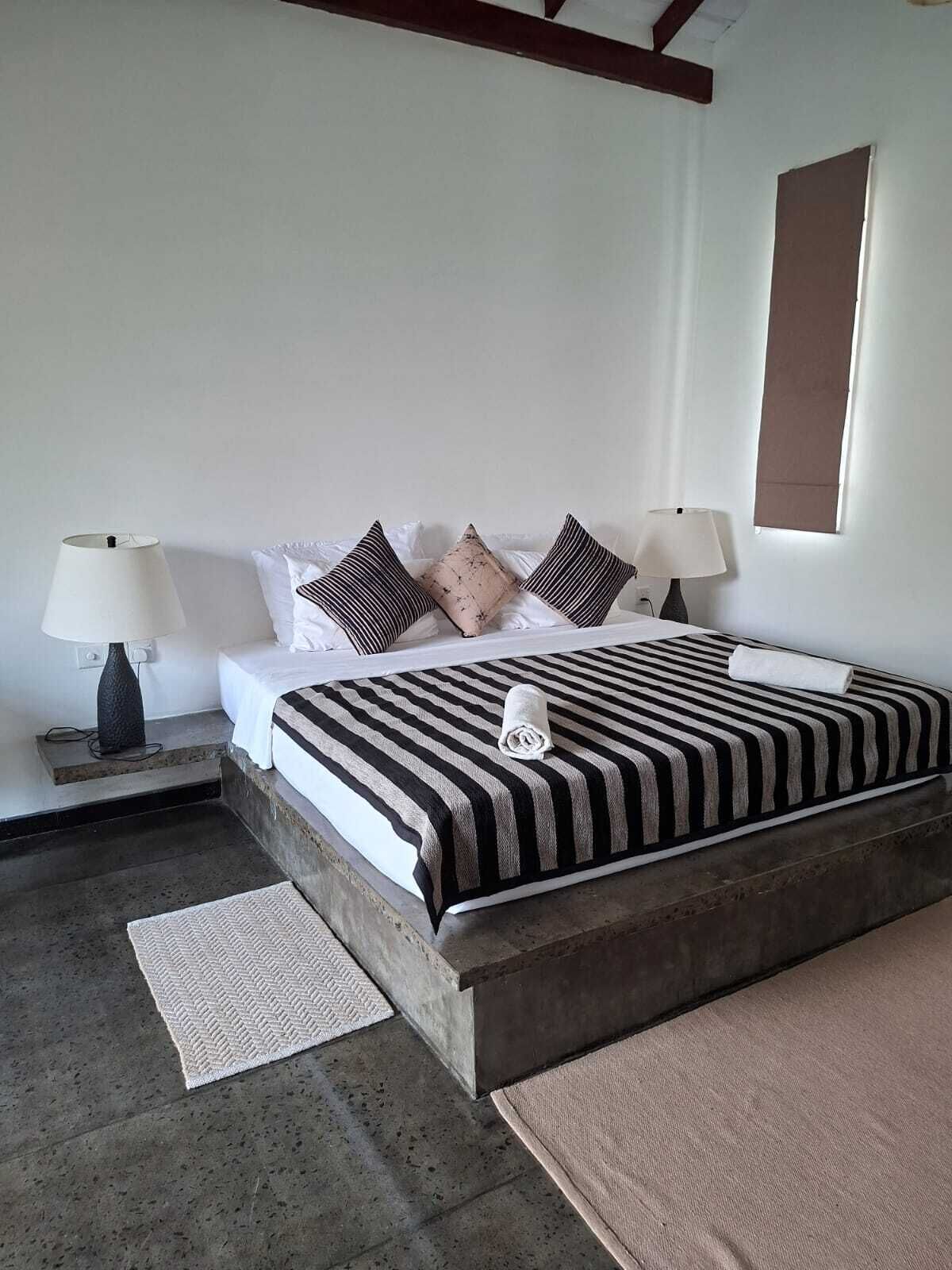 A bedroom with a bed, two bedside lamps, a window, and a door.