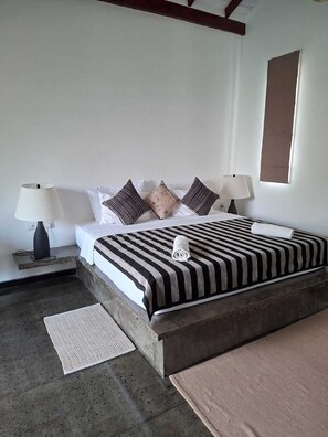 A bedroom with a bed, two bedside lamps, a window, and a door. - Wild Wadi wilpattu  (Eluwankulama)