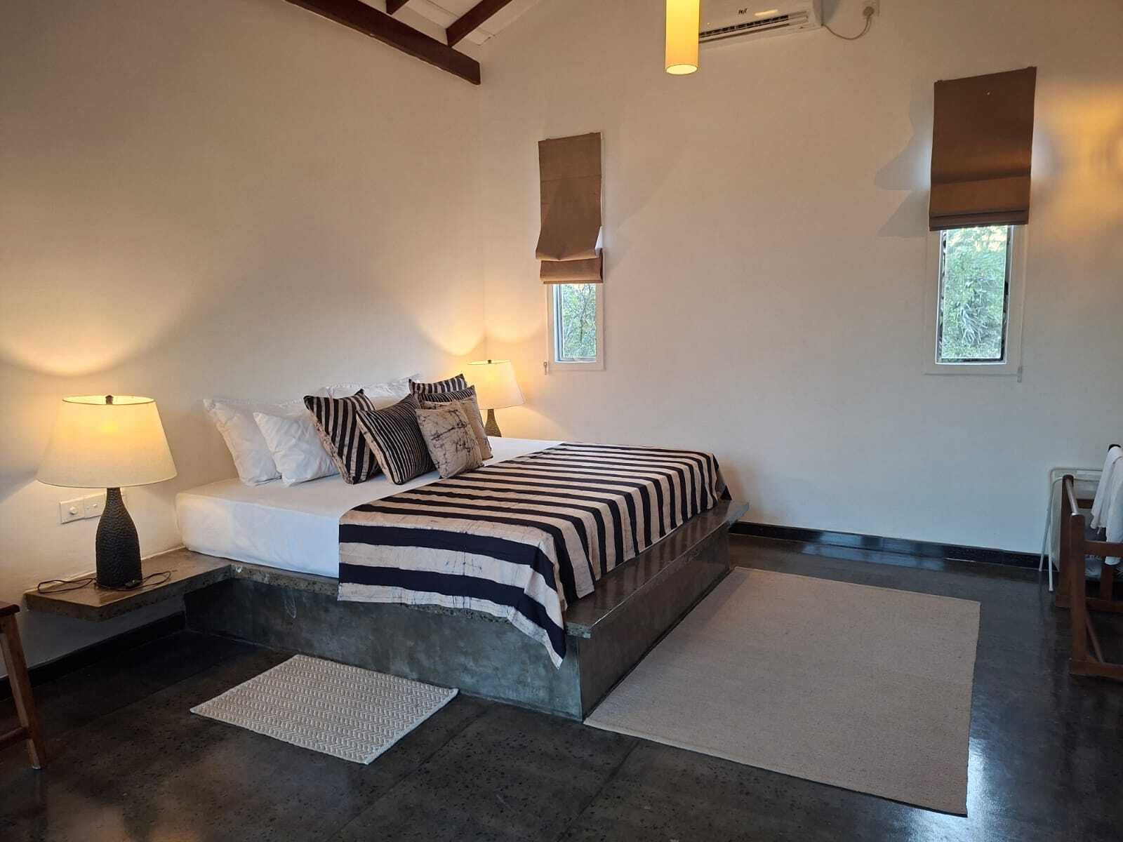 Un dormitorio con cama, dos lámparas de noche, una ventana y una puerta.