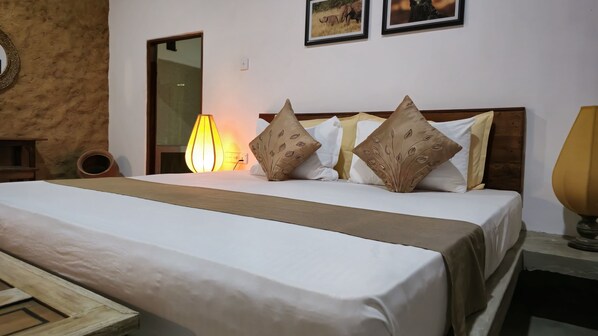 A neatly made bed with a wooden headboard, a bedside lamp, and two framed pictures on the wall.