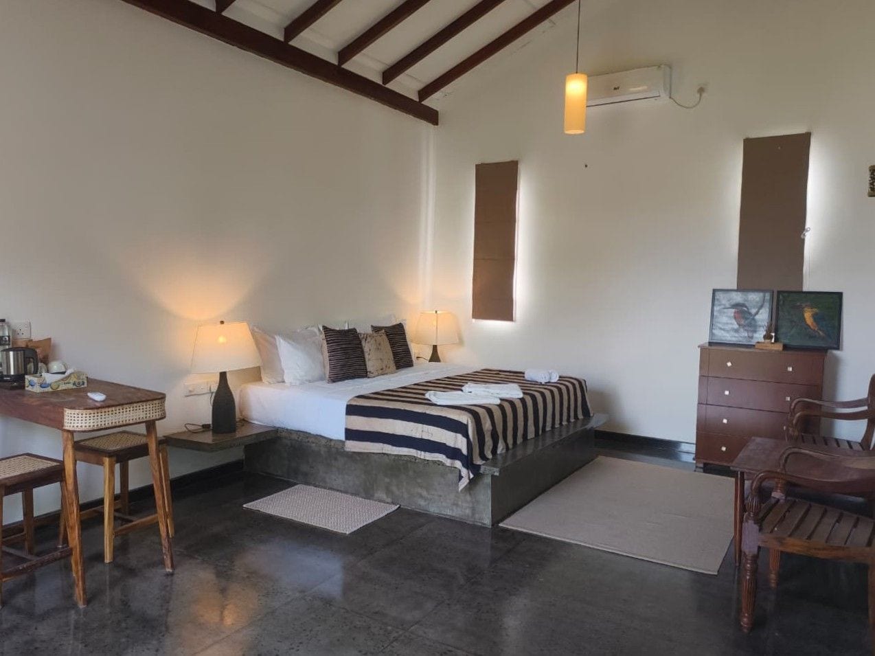 Un dormitorio con cama, mesitas de noche, escritorio, sillas y cómoda.