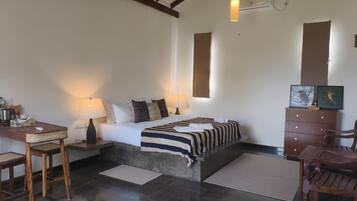 Un dormitorio con cama, mesitas de noche, escritorio, sillas y cómoda.