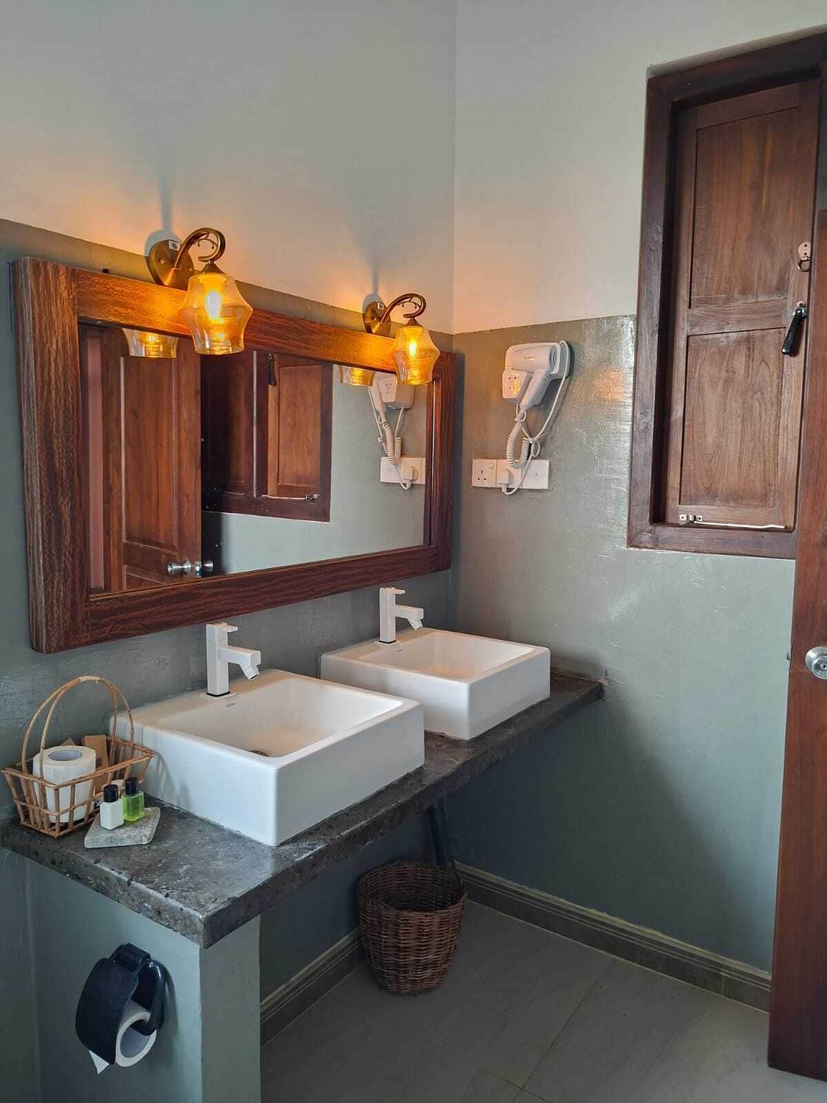 A bathroom with two sinks, a large mirror, and a hairdryer.