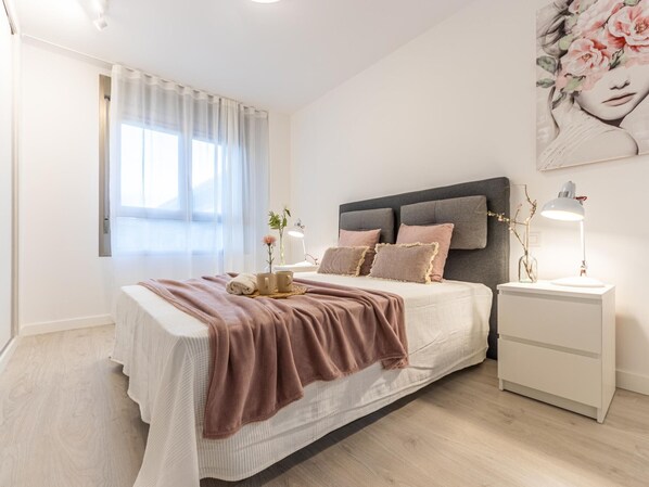 A modern bedroom with a large bed, bedside lamps, and a painting on the wall.
