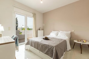 Un dormitorio con cama, una mesa, una silla, un radiador y vistas al exterior.