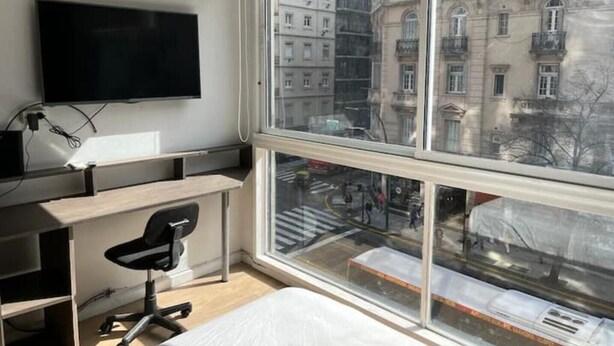 A modern hotel room with a large window, a flat-screen TV, a desk, and a chair. - Muy Bien Ubicado y Comodo (ABN)