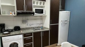 A compact kitchen with a washing machine, microwave, and refrigerator. - Muy Bien Ubicado y Comodo (ABN)