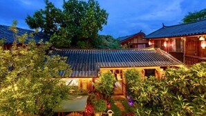 A traditional Japanese-style building with a tiled roof and wooden structure, surrounded by lush greenery. - fenghelijiang (Lijiang)