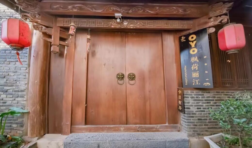 A wooden double door with a traditional design, flanked by red lanterns, and a sign with Chinese characters.