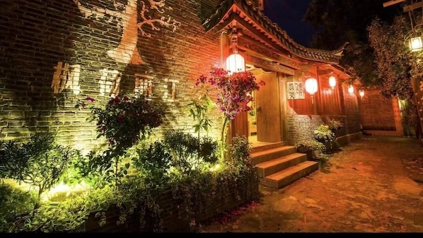 A traditional building with a brick facade, wooden steps leading to a door, and a lantern-lit entrance. - fenghelijiang (Lijiang)