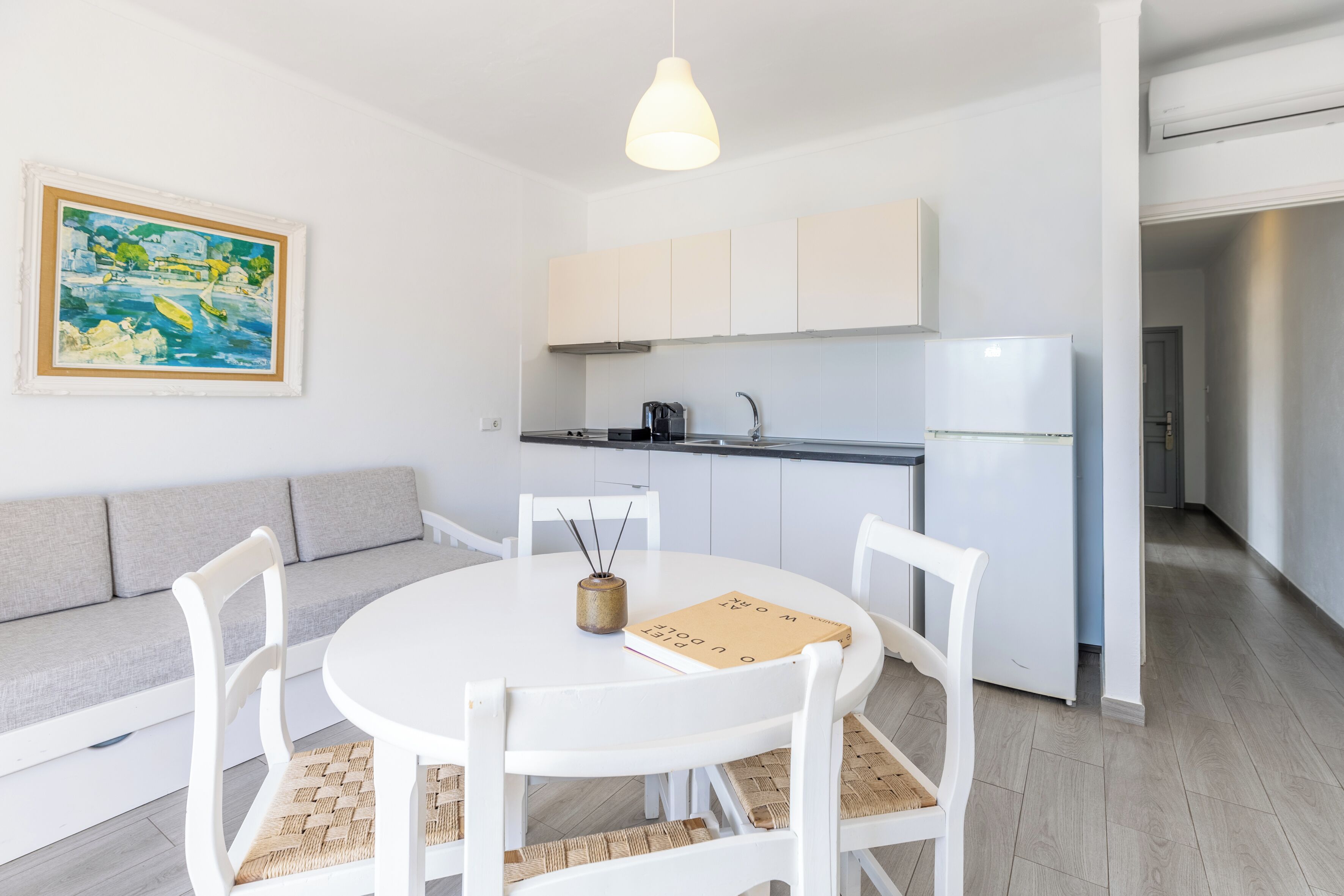 Een moderne keuken met witte kastjes, een ingebouwde oven en een hangende lamp.
