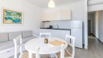 A modern kitchen with white cabinets, a built-in oven, and a hanging light fixture.