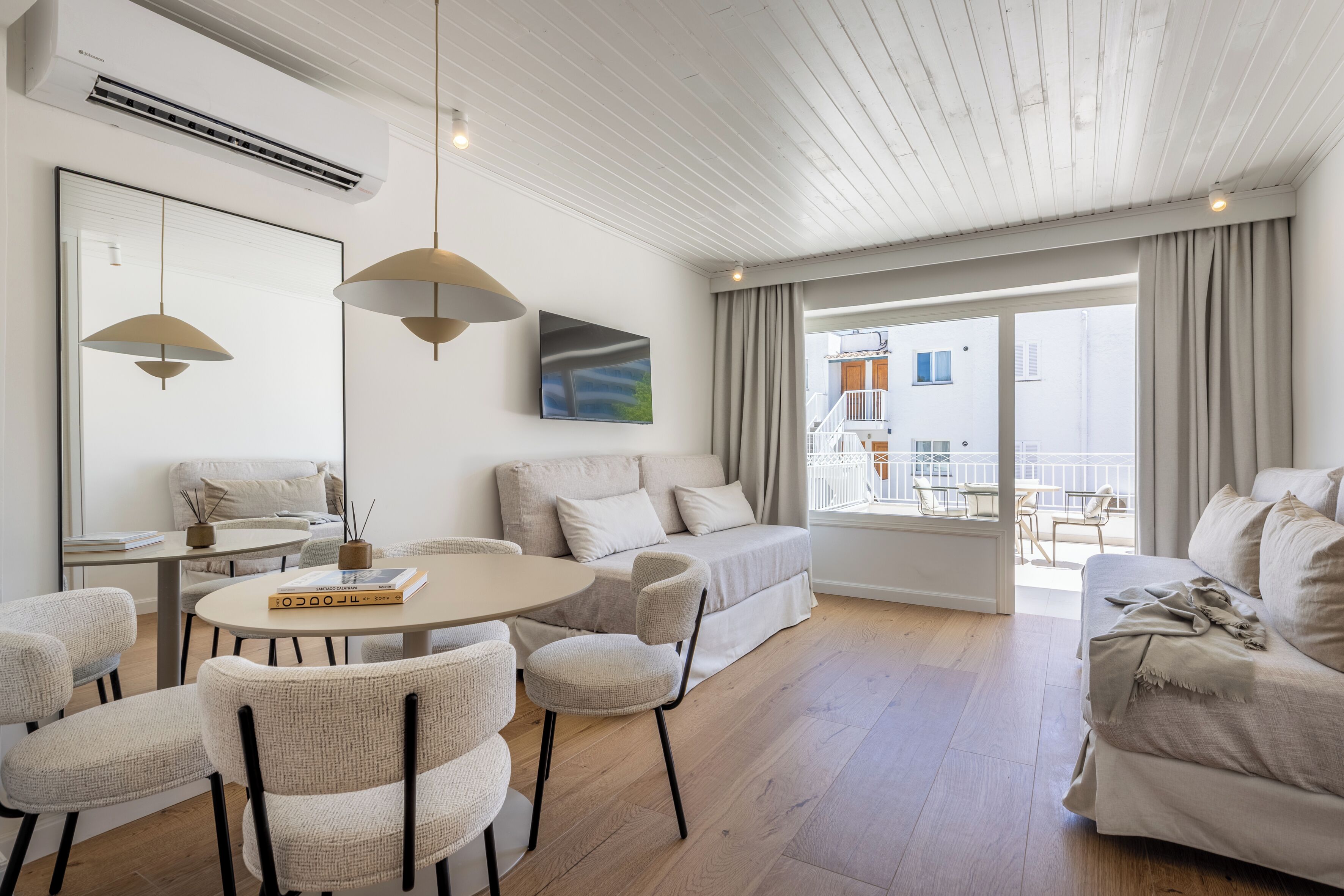 Un salon moderne avec une table ronde, des chaises, un canapé et un balcon offrant une vue agréable.